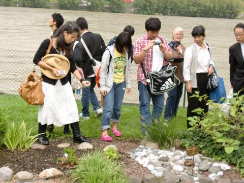 姉妹都市公園で多摩川の石を置く団員たち